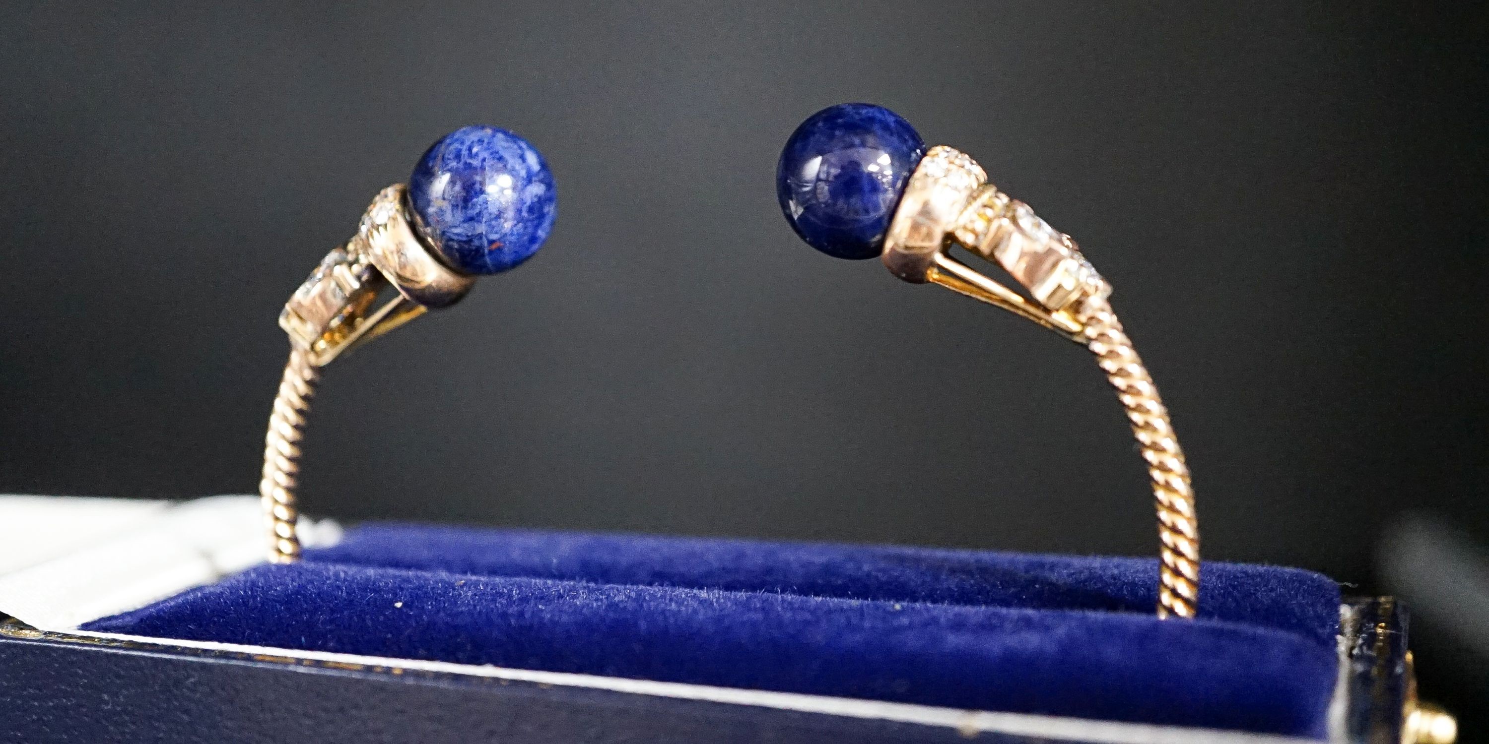 A modern yellow metal twist, two stone sodalite? and diamond set open bangle, gross weight 14 grams.